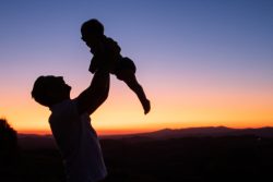 silhouette of man lifting a child up in air